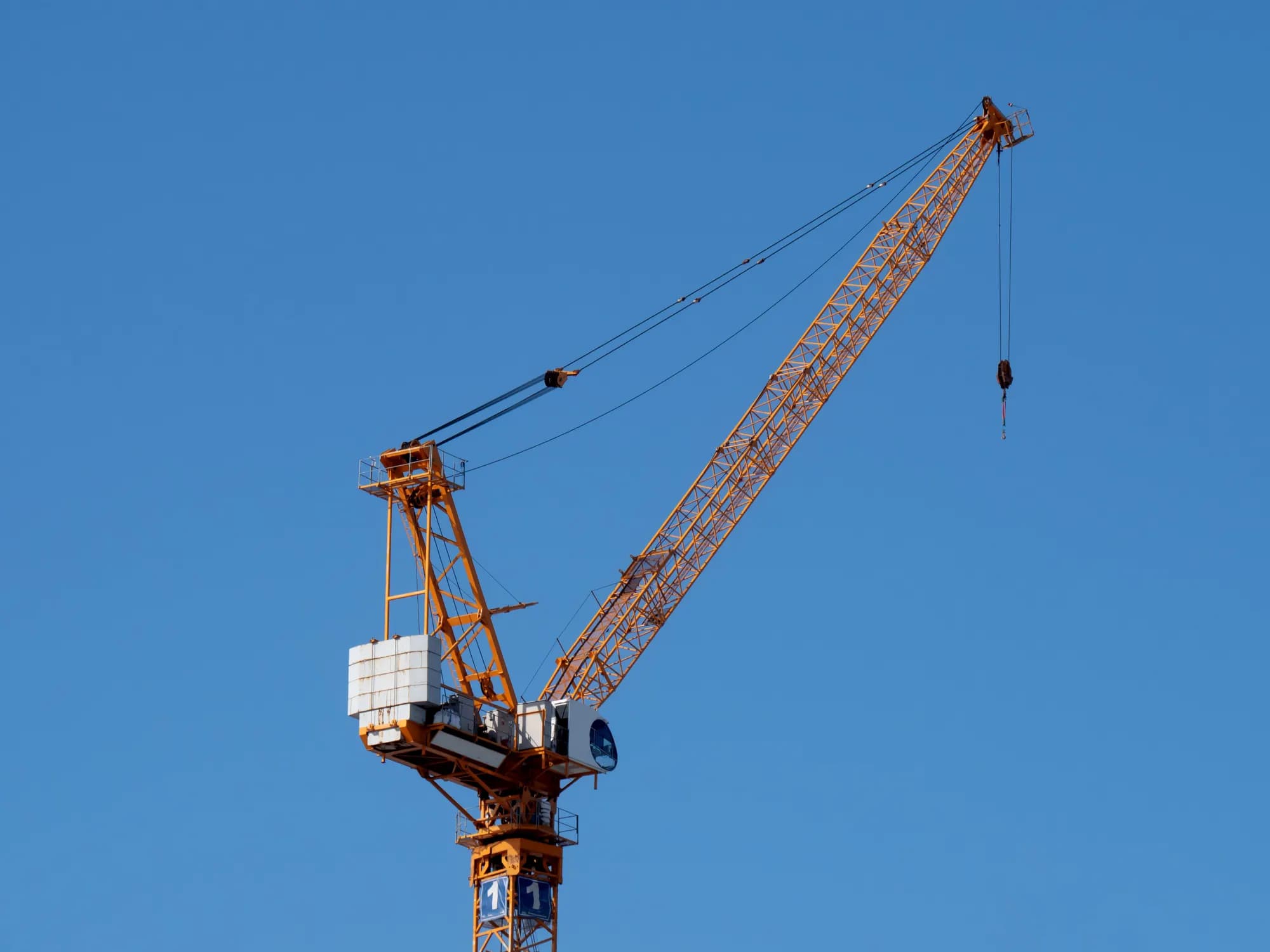 Tower crane against a clear blue sky on a high-rise construction site